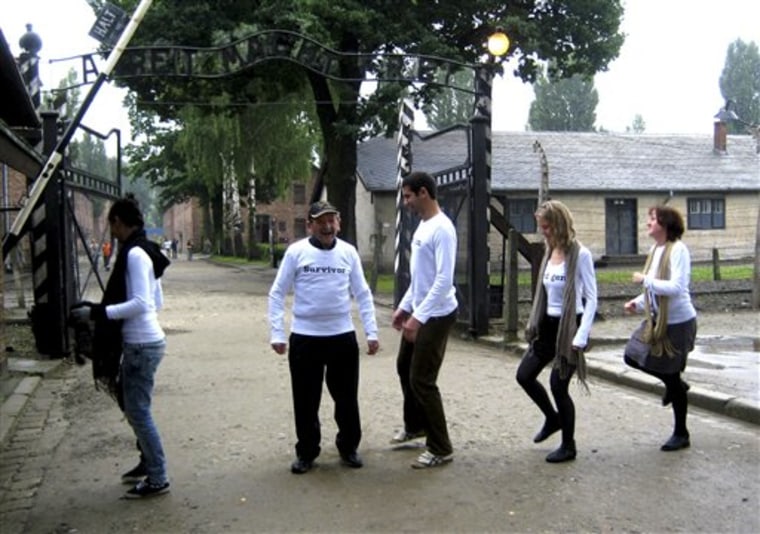 Holocaust survivor Adolek Kohn stands with his grandchildren at the entrance gate to the Auschwitz death camp in Poland in this undated image, taken during the making of a clip in which he is dancing with his family on what easily could have been his own grave. The 4 1/2-minute clip of Adolek Kohn and his loved ones stiffly shuffling and shimmying to the disco hit, \"I Will Survive,\" at Auschwitz and other places where millions died during the Holocaust has become a surprise hit on YouTube, sparking a fierce debate over whether it disrespects those who perished or is an exuberant celebration of life.(AP Photo/Jane Korman)